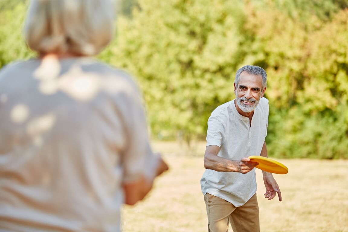 Active seniors playing with a frisbee in summer in the nature